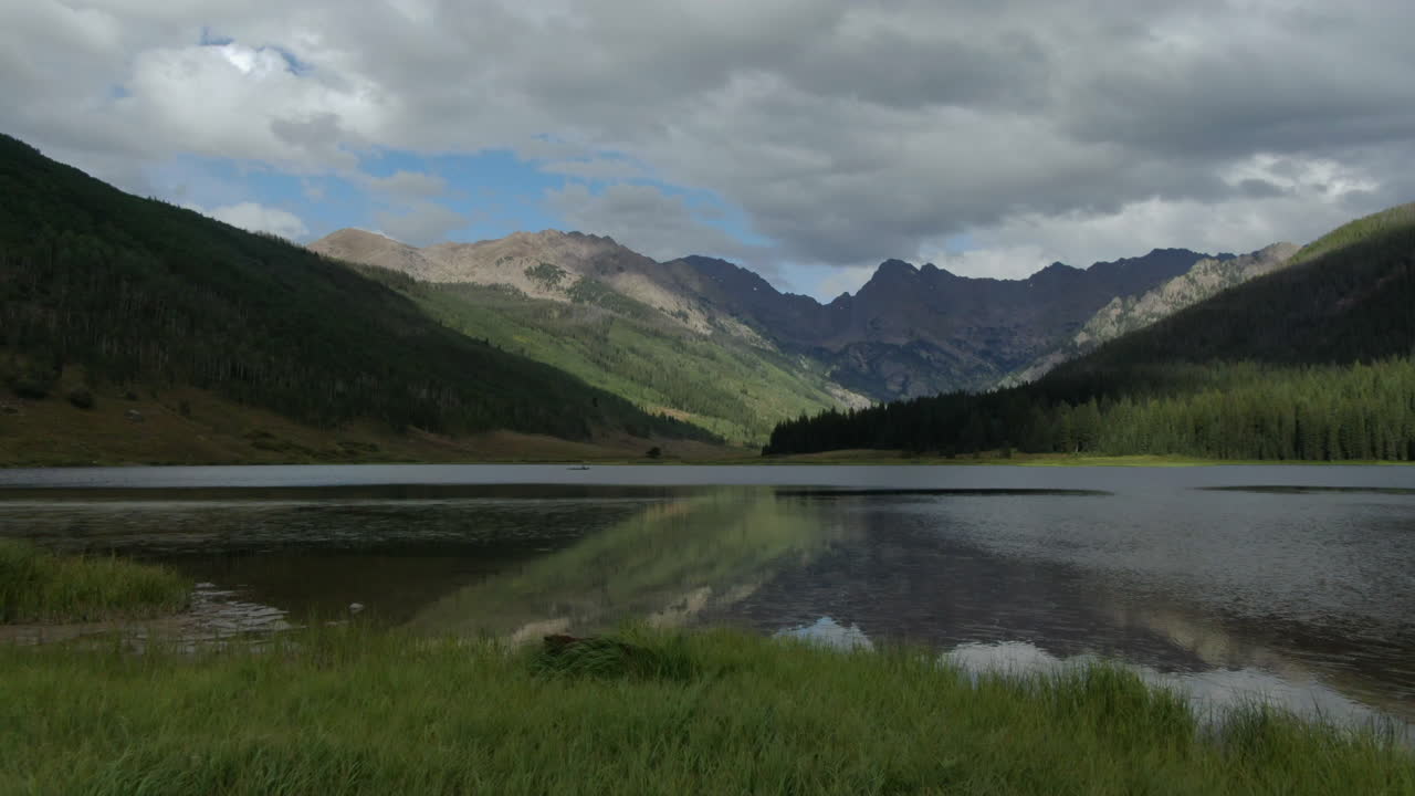 Aerial cinematic drone Piney Lake Ranch Vail Beaver Creek Avon Colorado Gore Range mountain landscape late summer afternoon sun and rain clouds stunning peaceful green grass calm slide to the right