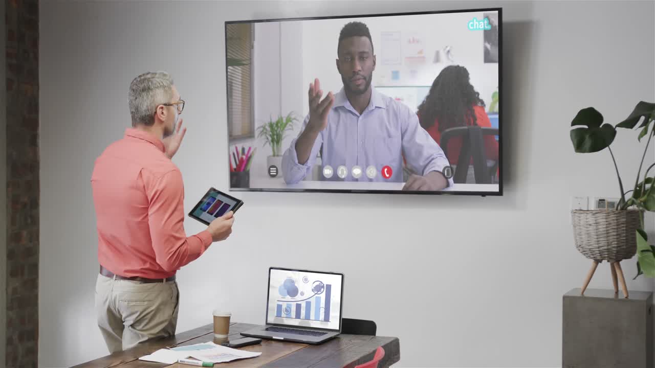Caucasian businessman on video call with african american male colleague on tv screen