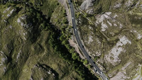 tomada de arriba hacia abajo de coches conduciendo a través del campo rural y rocoso de escocia