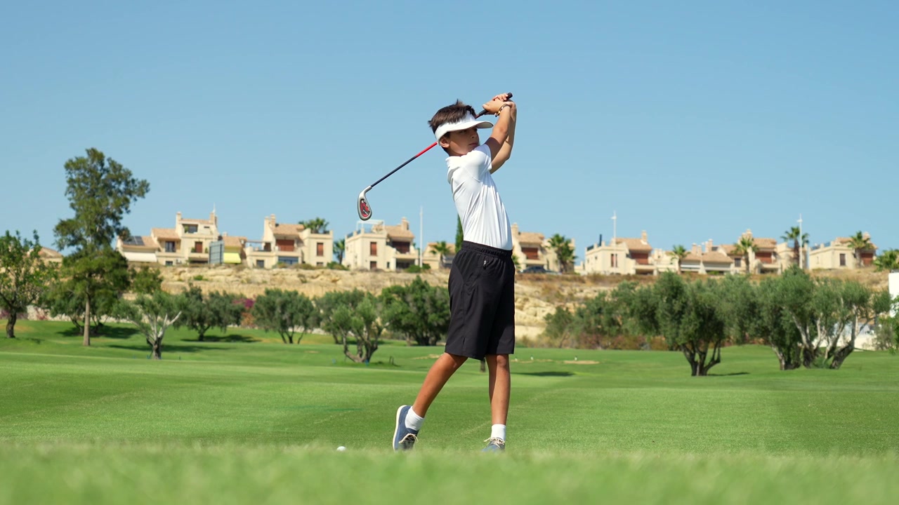 Young Boy Practicing Golf Swing on Sunny Course
