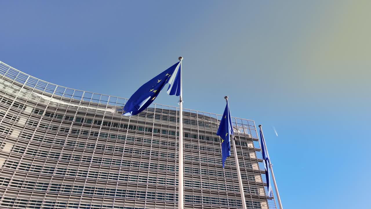 Inquadratura dal basso di bandiere dell'UE sotto un cielo blu limpido a Bruxelles