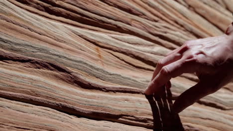 human hand touching layered sandstone rock formation