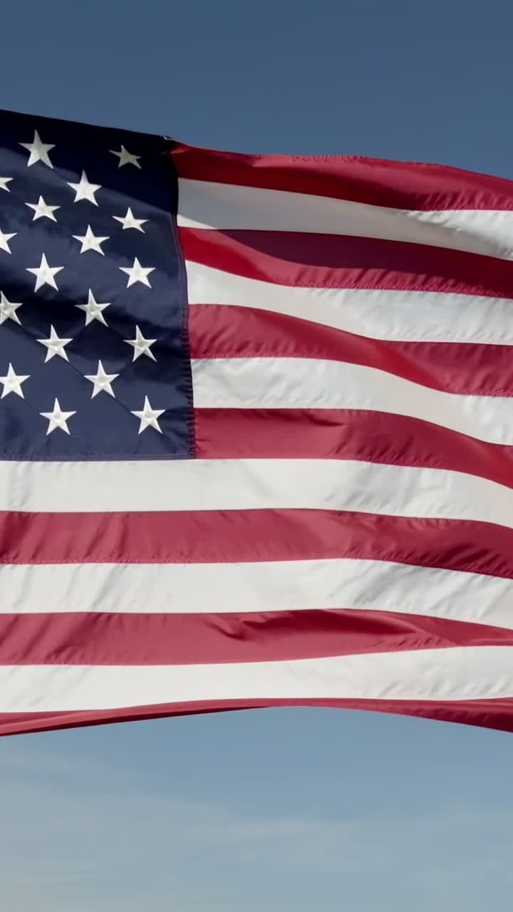 Vertical video: Responding to gentle breeze, US flag undulating against sky, with stars and stripes