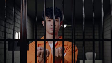 close up of asian male prisoner stretching out the hands surrender himself while standing in prison