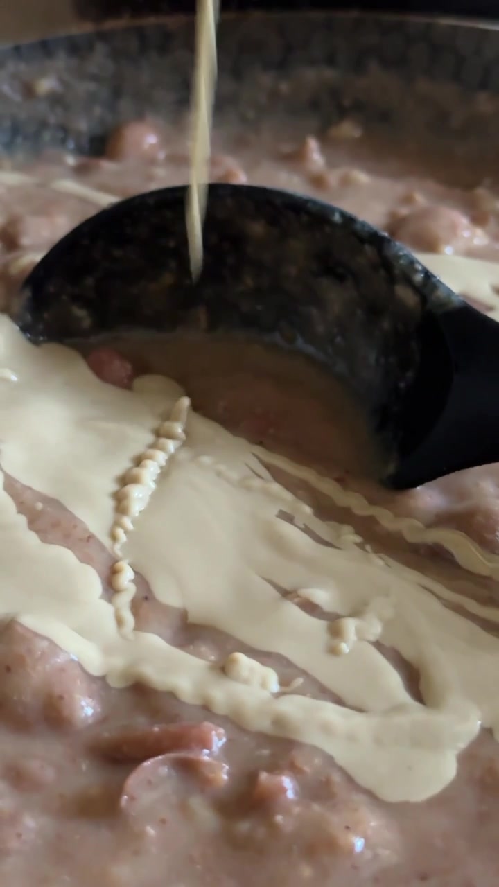 beans being poured into a pan with simmering stew during home cooking, close up shot, insert shot