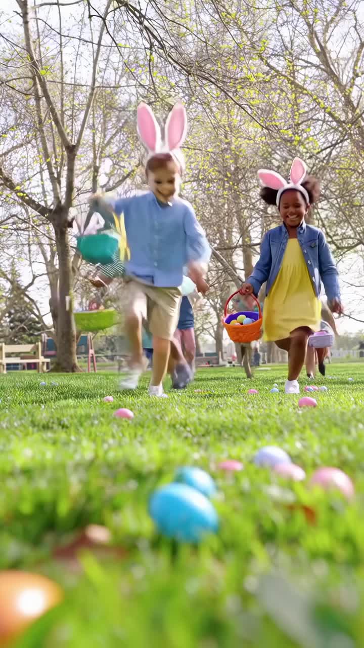 子供たちが公園でイースターエッグを集め、草の上をうれしそうに走っているローアングルの動画