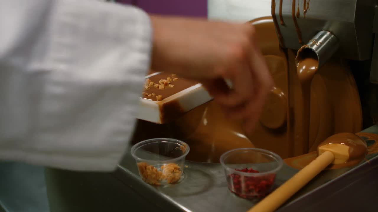 녹은 초콜릿 위에 견과류를 뿌리는 노동자