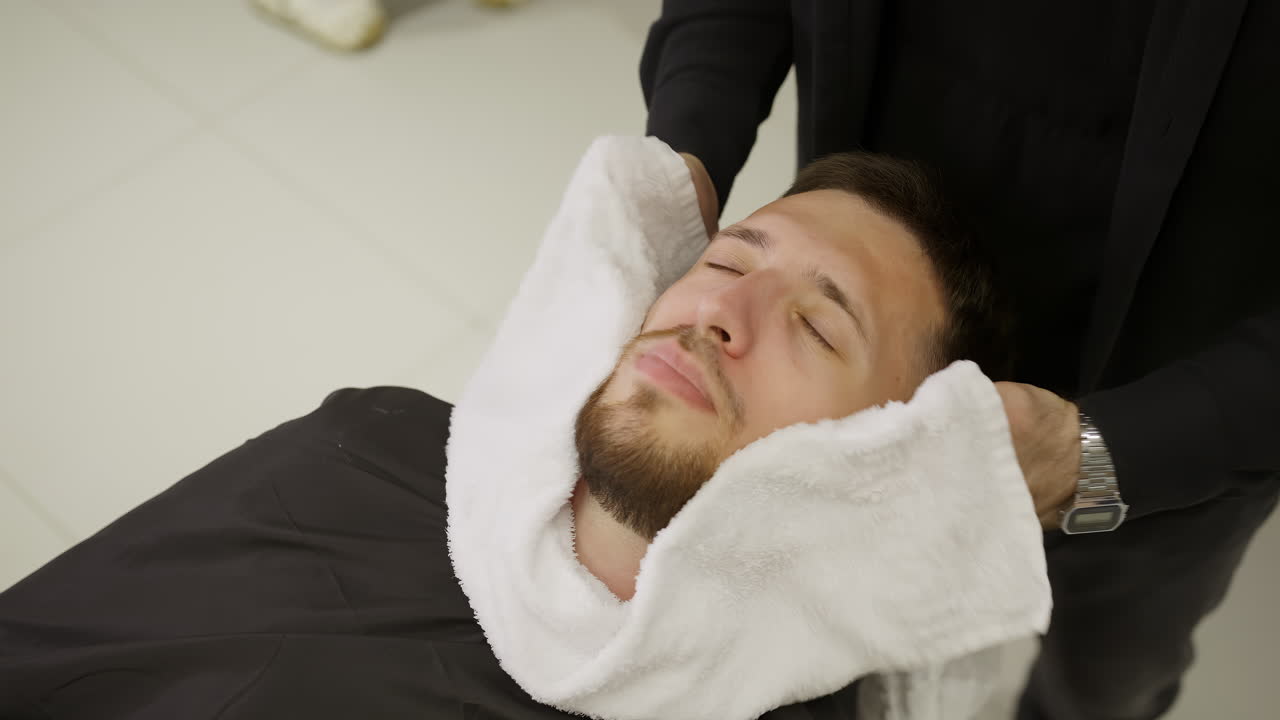 Man getting a hot towel treatment at a barbershop