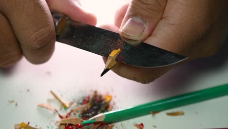 Footage-of-hands-slowly-sharpening-a-pencil-and-some-coloured-pencils-with-a-sharp-knife