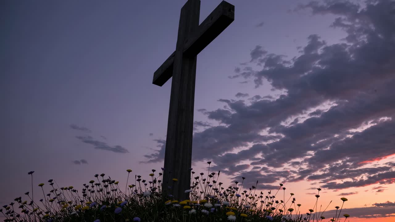 Ripresa dal basso di una croce contro un cielo drammatico al tramonto, circondata da fiori selvatici, che evoca una sensazione serena
