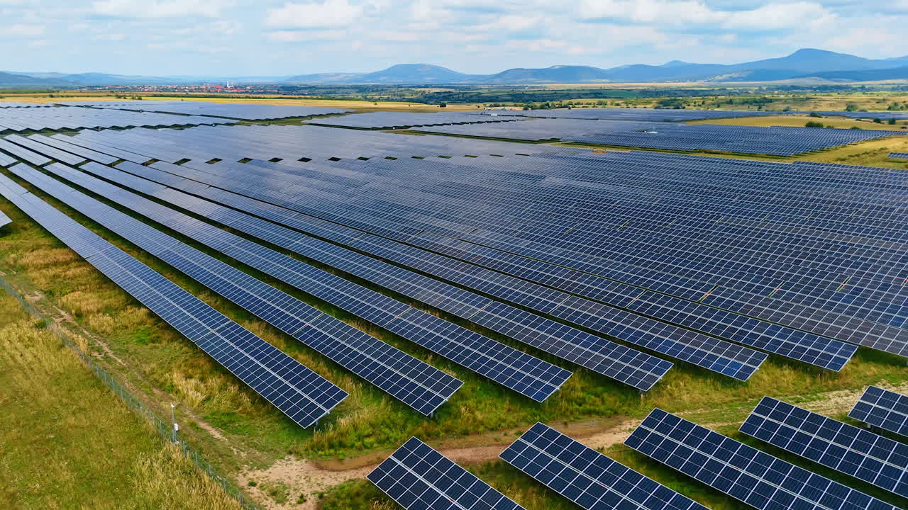 Solar power field under blue sky and clouds. Aerial image of a solar panel field producing renewable electricity on a sunny day with scattered clouds