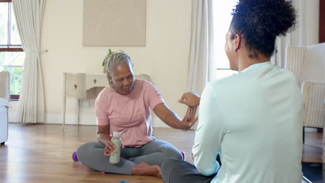 senior woman sitting on floor with carer, smiling and enjoying conversation at home