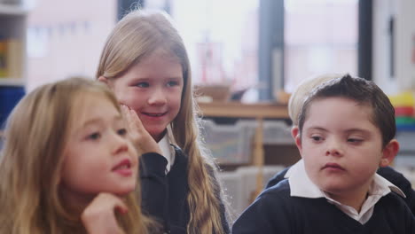 Four-primary-school-kids-sitting-in-class-listening-and-raising-hands-to-answer,-close-up,-backlit