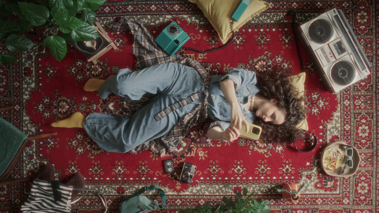 Vista dall'alto di una giovane donna che si scatta un selfie con il telefono su un tappeto vintage