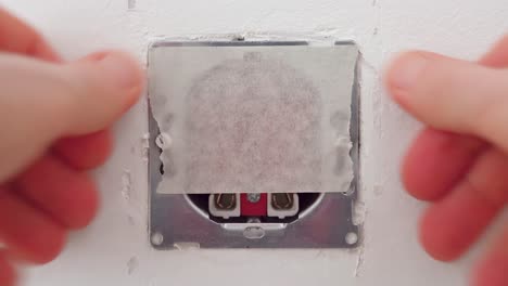 man covering a wall outlet with masking tape