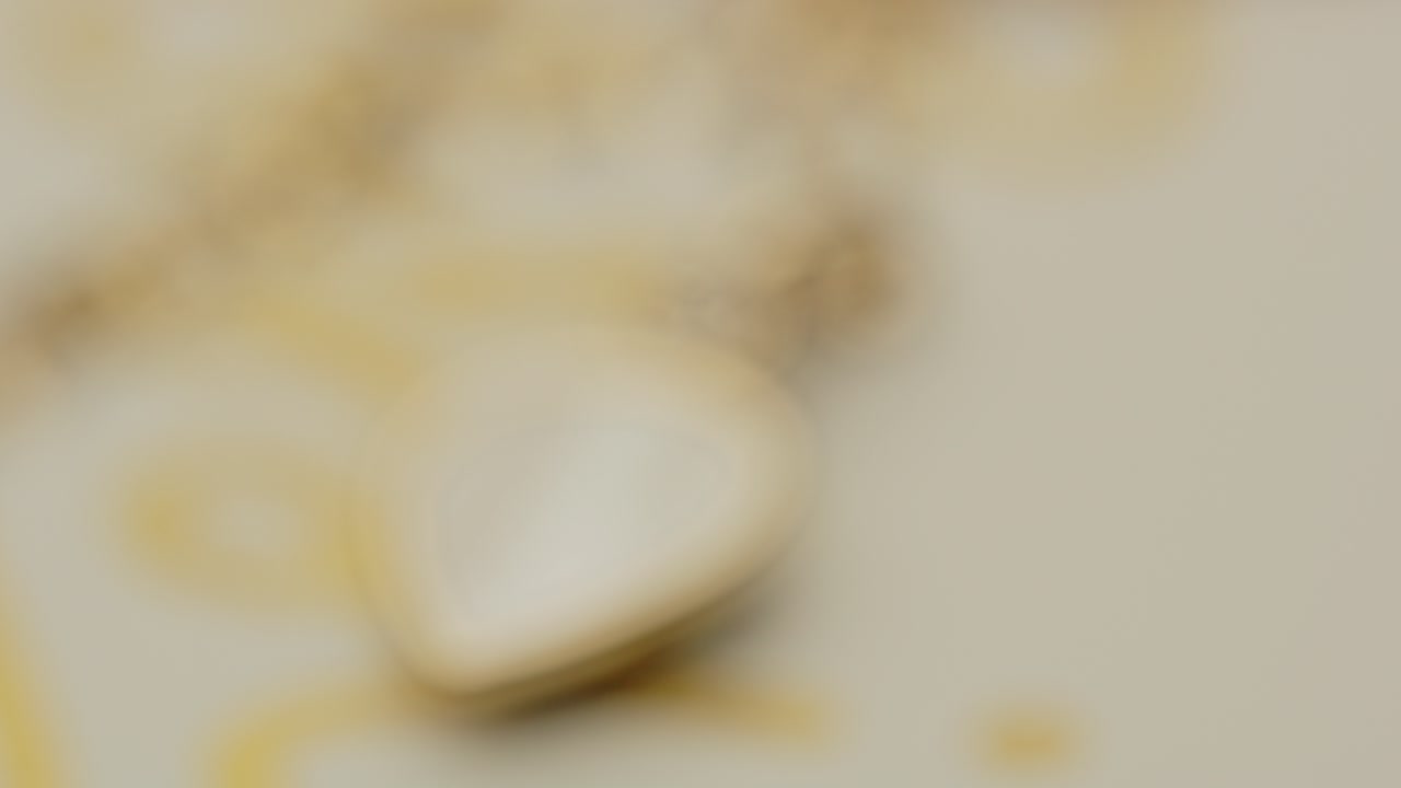 목걸이에 달린 아름다운 황금 금속의 매크로가 천천히 초점을 벗어나고 있습니다.