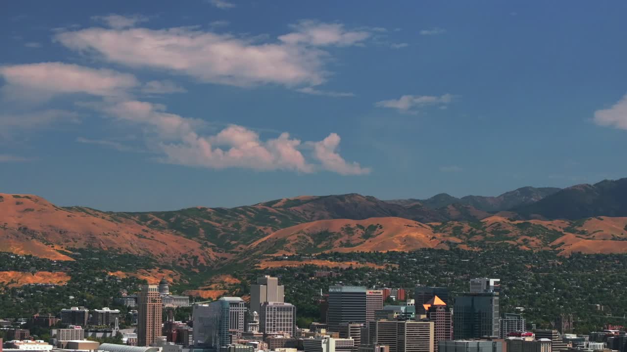 Downtown Salt Lake City SLC Utah USA Wasatch Mountain Range aerial drone opening scene pan down summer blue sky morning afternoon LDS temple The Great Salt Basin Lake County region office buildings