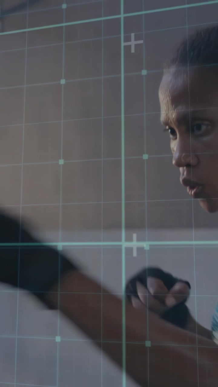 Vertical video: On cue female boxer throwing punches, wraps visible, turquoise grid tracking form