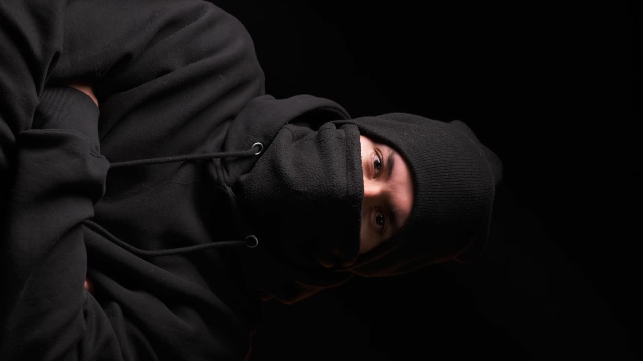Thief staring at the camera while standing on a dark background.
