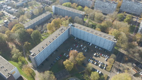 aerial orbit of social housing flat with parking lot and green park in autumn