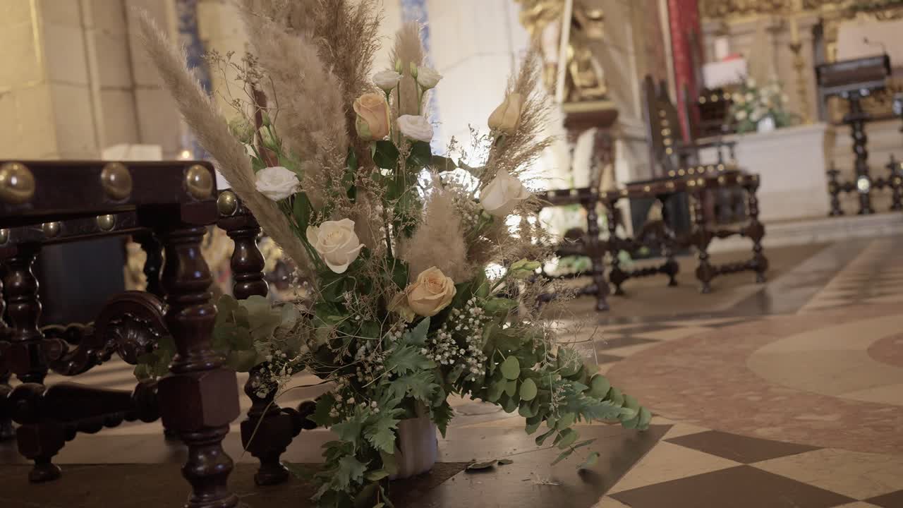 soft beige and white rose bouquet with pampas grass placed inside a historic church aisle