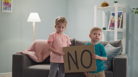 una niña y un niño fruncidos con un cartel