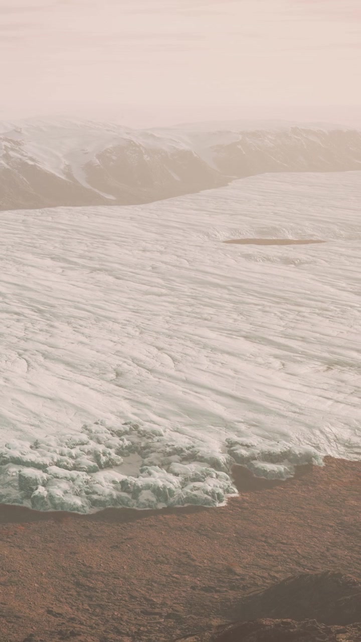 Glacier covers vast landscape with mountains in the background at sunrise