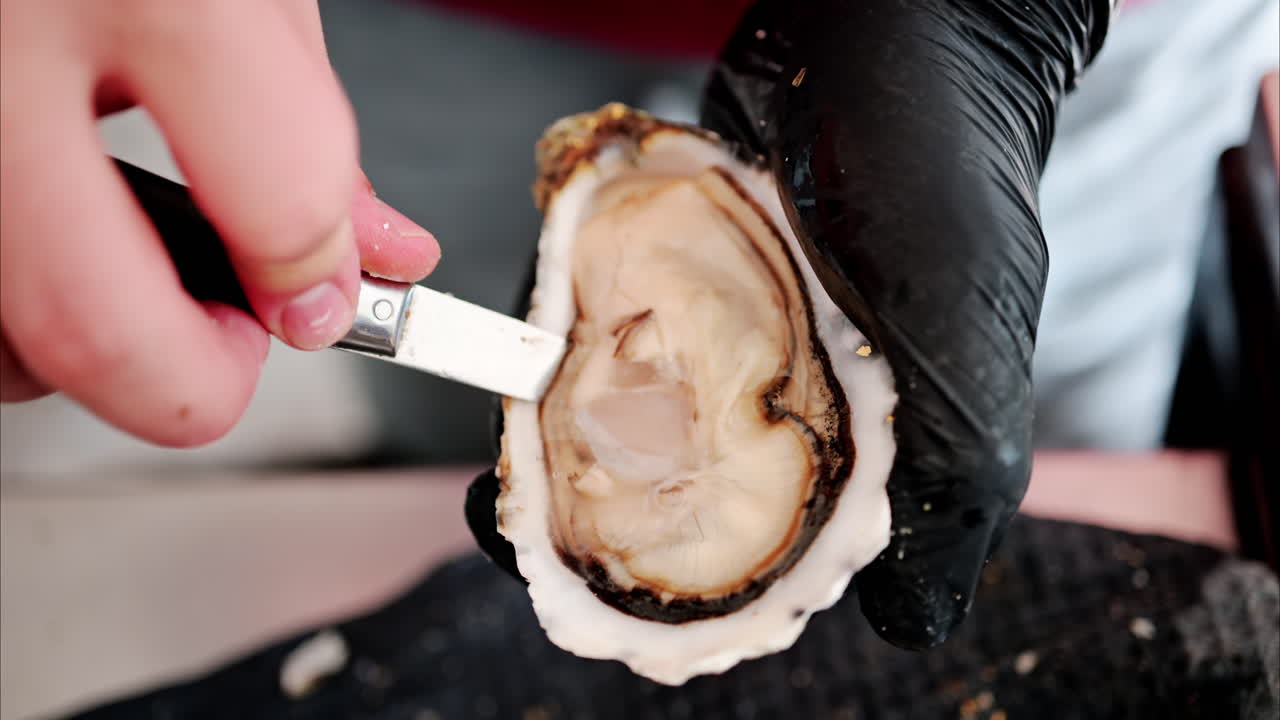 Close up of a waiter cutting a raw oyster at a restaurant