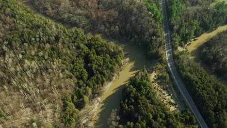 Langsamer,-Schmutziger-Fluss,-Der-Sich-Durch-Den-Dichten-Wald-Mit-Ländlicher-Landstraße-Und-Brücke-Schlängelt