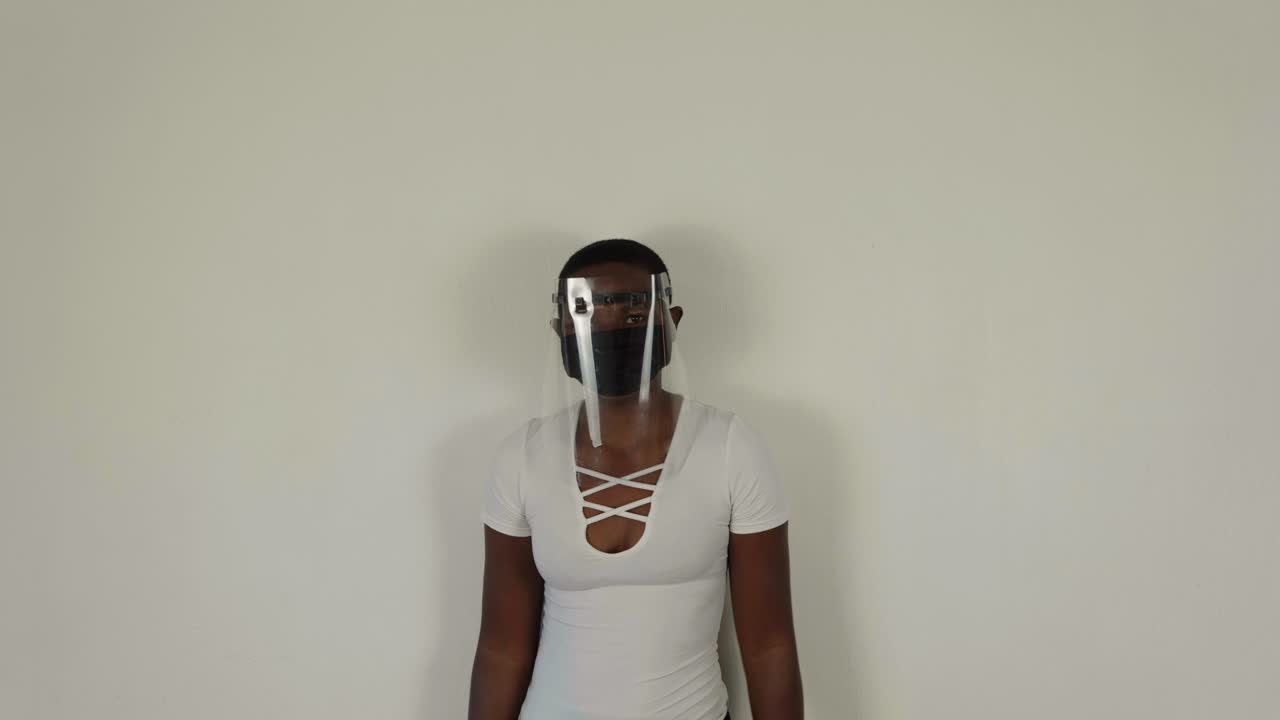 African lady putting on a visor while wearing a mask for covid-19