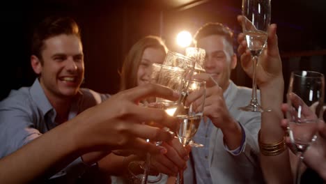 Group-of-smiling-friends-sitting-on-sofa-and-toasting-a-glasses-of-champagne