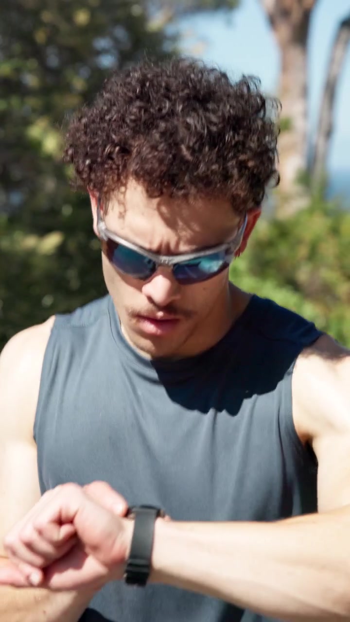 Young Man Running Outdoors and Checking His Smartwatch