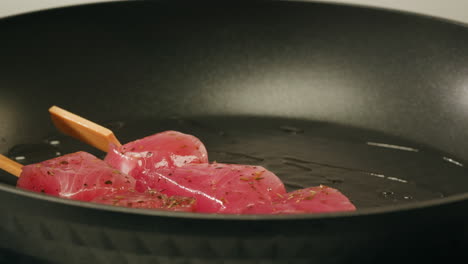 cooking tuna skewers in a pan