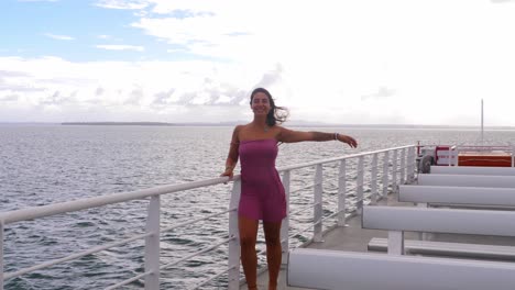 niña caucásica de pie y agarrándose a las barandillas de la cubierta del ferry mientras levanta la otra mano - ferry que se dirige a la isla de north stradbroke, queensland, australia