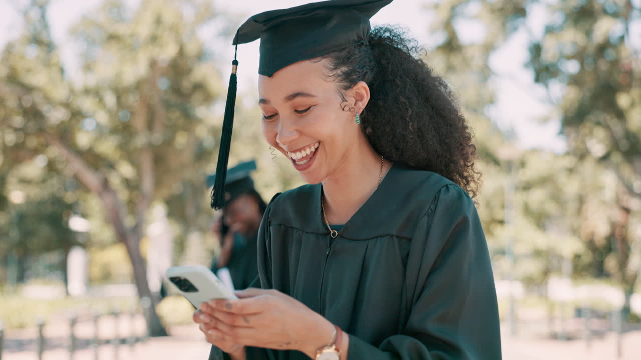 feliz graduado comprobando el teléfono