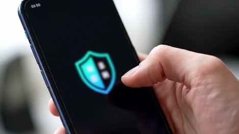 a close-up of a hand interacting with a smartphone display featuring a colorful shield icon, symbolizing security, protection, and digital safety in modern technology