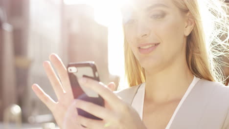 Hermosa-Mujer-Rubia-Usando-El-Concepto-De-Energía-Solar-De-La-Luz-Solar-De-La-Llamarada-Del-Teléfono-Inteligente