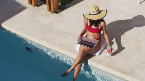 Mixed-race-woman-sitting-by-a-pool-at-home