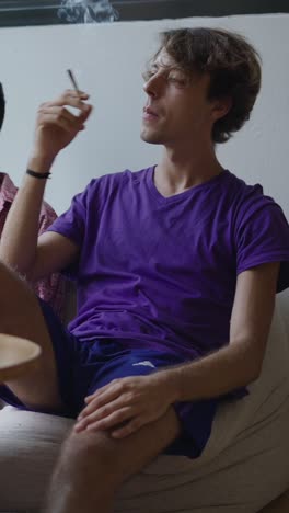 man sitting on beanbag in purple shirt and blue shorts