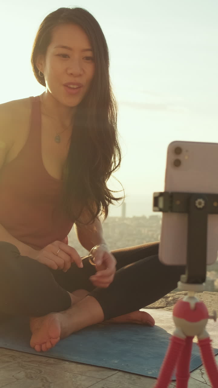 Woman doing yoga and filming a video with her phone