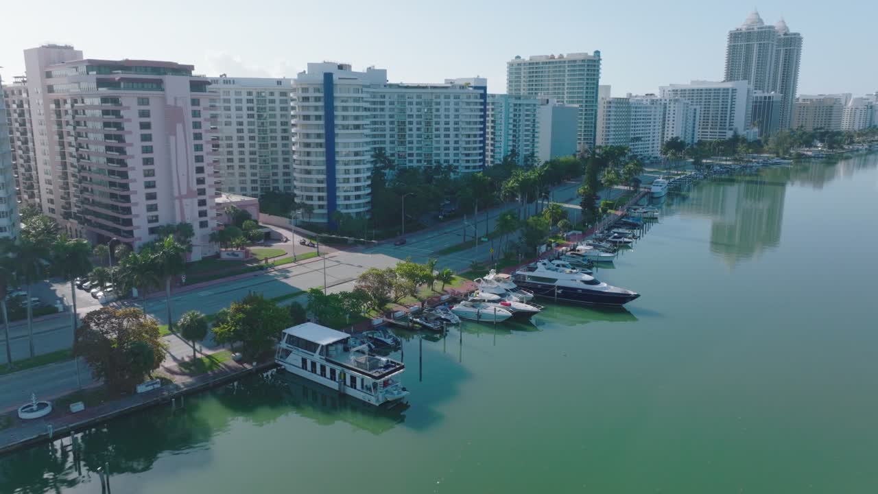 yates amarrados a lo largo de la orilla. vista aérea del arroyo y la carretera de varios carriles que conduce a lo largo de altos edificios residenciales. miami, ee.