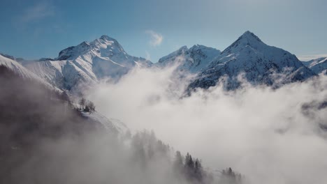 Video-Einer-Drohne,-Die-Durch-Die-Wolken-Auf-Eine-Schneebedeckte-Bergkette-Zufliegt