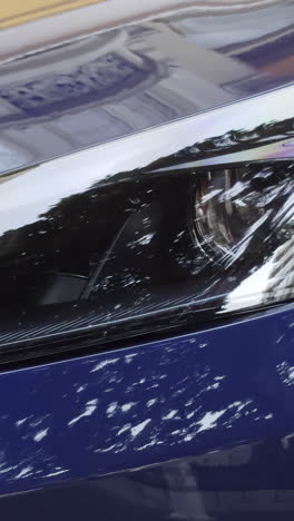 close-up of a blue car's headlight and front bumper
