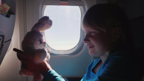 the girl is traveling on a plane with her favorite toy happy childhood and vacation with the baby co