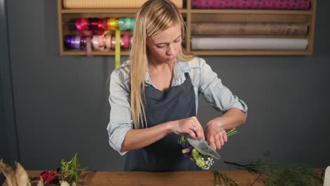 joven florista hermosa envolviendo un ramo de flores en papel de decoración. disparo en cámara lenta