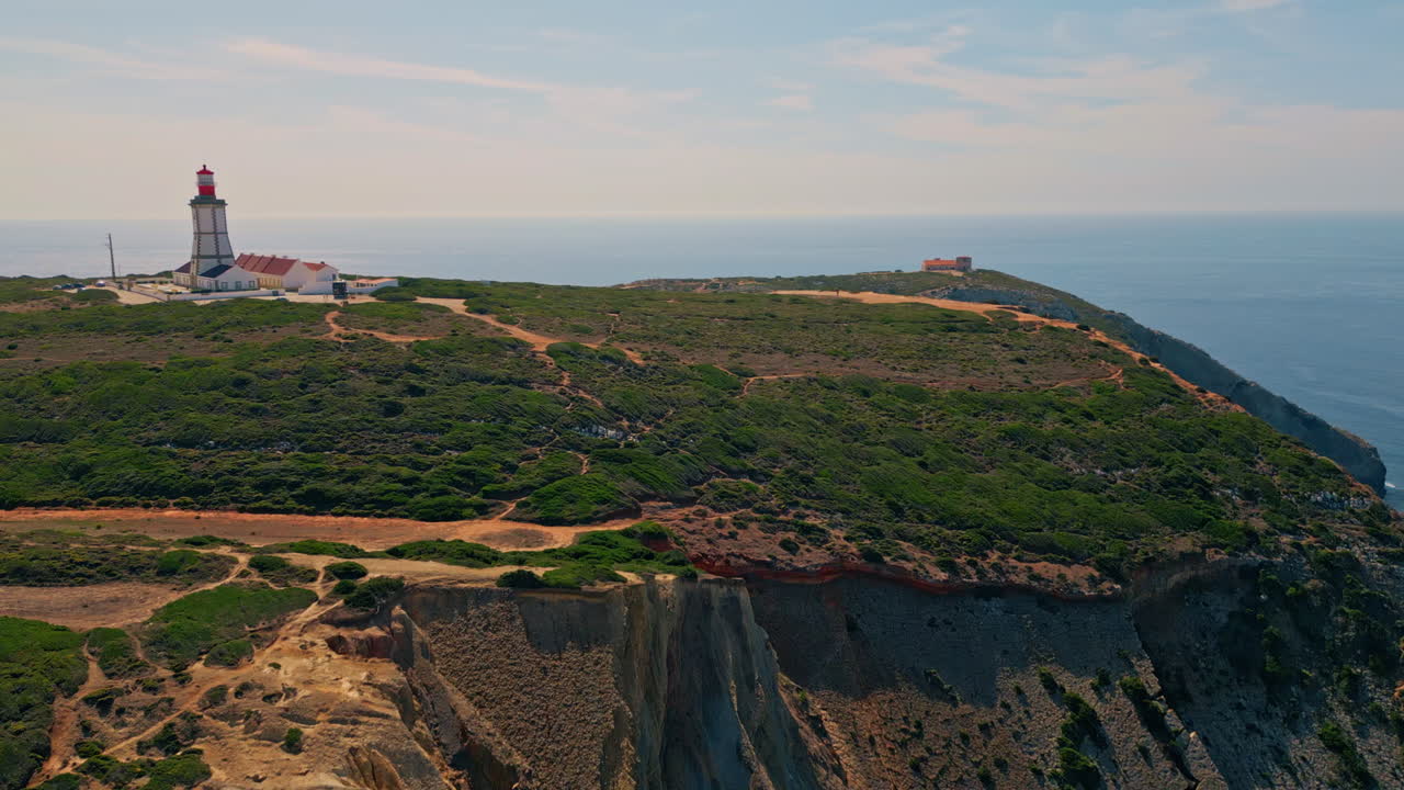 Aerial  coastal panorama with lighthouse rising at ocean shore cliff
