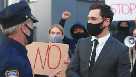 geschäftsmann, der aus protest gegen covid 19 auf der straße einen polizisten anschiebt und anschreit