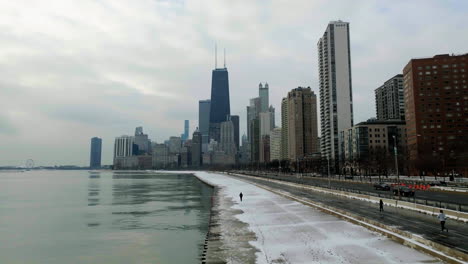 aerial view following a person walking on the concrete beach towards skyscrapers in streeterville, chicago, usa