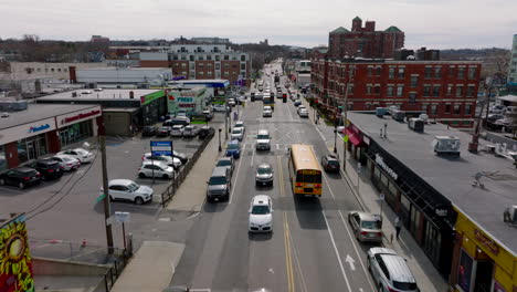 Vorwärtsverfolgung-Eines-Typischen-Amerikanischen-Gelben-Schulbusses,-Der-An-Einer-Ampel-An-Einer-Belebten-Straße-In-Einem-Städtischen-Viertel-Hält.-Boston,-USA