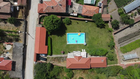 a backyard pool surrounded by homes on a sunny day, aerial view from above